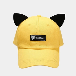 Detail of yellow cotton baseball cap with black cat ears and handmade woven label