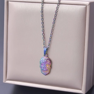 Macro detail of rainbow plated skull pendant with intricate floral engravings on a necklace