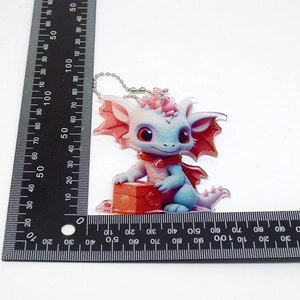 Detailed size view of a cartoon blue dragon acrylic ornament with a ruler on white background