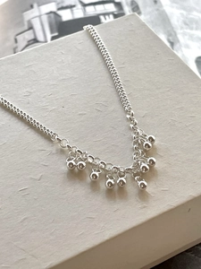 Close-up of minimalist 925 sterling silver beaded bracelet on white textured box