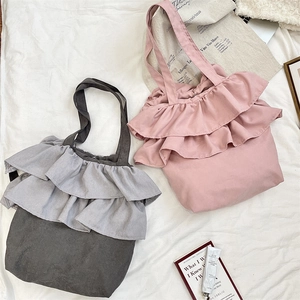 Detail view of ruffle canvas tote bags in grey and pink on a lifestyle aesthetic background
