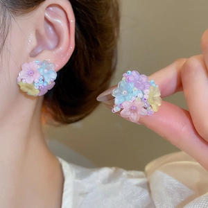 Détail de boucles d'oreilles fleurs perlées avec pétales en résine macaron pastel