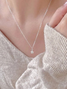 Detail of minimalist 925 sterling silver star necklace worn on a woman's collarbone