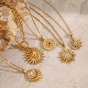 Set of five gold stainless steel sun and star necklaces on a minimalist stone background