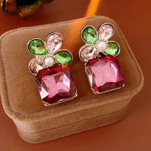 Close-up of vintage flower earrings with ruby square gemstone on brown velvet box