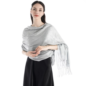 Close-up of shimmering silver evening shawl with elegant fringe detail on white background