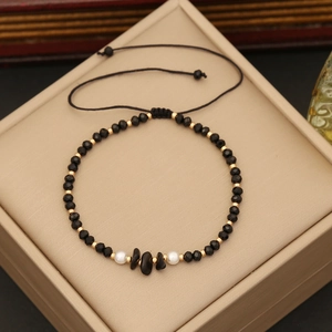 Detail of beaded bracelet with black natural stones and gold beads on a jewelry box