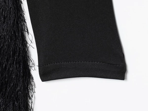 Gros plan détaillé des franges noires et des coutures soignées sur l'ourlet de la robe