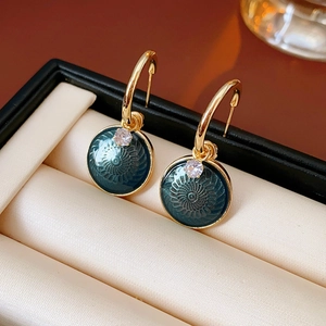 Detailed close-up of vintage flower earrings with dark green enamel in a jewelry box