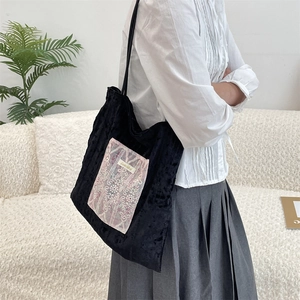 Detail of bohemian floral pattern pocket on black canvas shoulder bag with slim straps