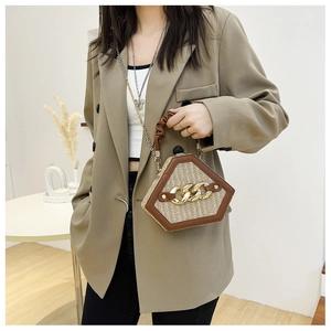 Close-up of hexagonal straw handbag with leather trim and chunky metallic chain strap