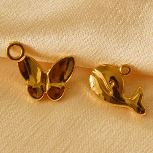 Macro detail of golden butterfly and whale charms on luxury champagne silk fabric