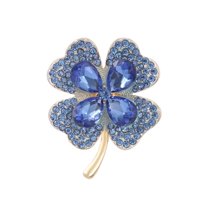Elegant gold four-leaf clover brooch featuring pear-shaped blue crystals and pave rhinestones
