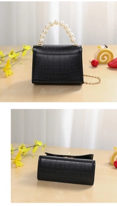Detail of black crocodile texture mini bag with pearl handle and golden chain strap