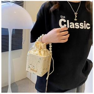 Detailed close-up of woven bucket bag with pearl handle and floral embroidery