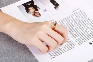 Dettaglio di un anello dorato con pietra tonda trasparente sulla mano della modella