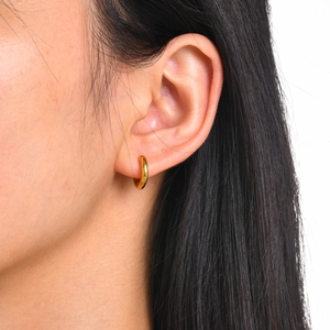 Close-up of small 18k gold plated stainless steel hoop earring on a model's ear lobe