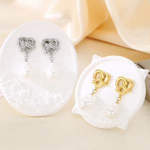 Elegant gold and silver heart knot earrings with baroque pearl drops on white stands