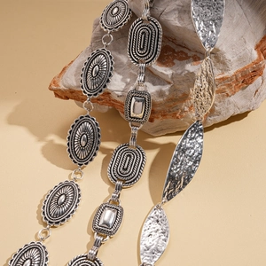Vintage silver geometric metal waist chain with embossed oval and leaf charms on rock