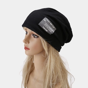 Détail du bonnet en maille côtelée noire avec patch gris et lettrage décoratif