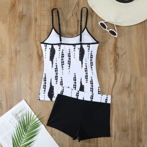 Flat lay of a black and white print tankini set with high waist bottoms on a wooden surface