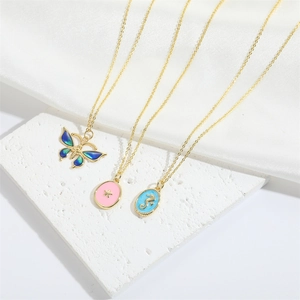 Three gold butterfly, star, and seahorse pendant necklaces on white silk and stone