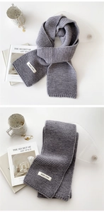 Detail of gray knitted scarf showing thick ribbed texture and white fabric label