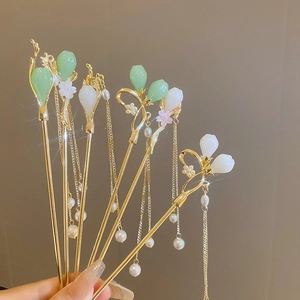Détail d'épingles à cheveux dorées avec bourgeons en jade, perles et longs glands