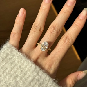 Detailed macro view of an oval cut gemstone ring with diamond accents on a model's hand
