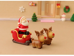 Miniature resin Santa Claus in a red sleigh pulled by two reindeer figurines