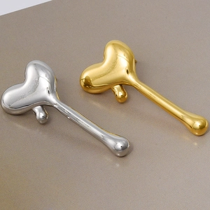 Macro shot of liquid metal heart earrings in gold and silver finish with sleek long posts