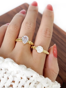 Detail view of gold beaded rings with pear and round sparkling zircon stones on a model