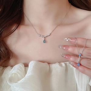 Close-up of s925 silver necklace with pear-shaped blue zircon pendant on model