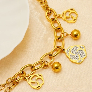 Detailed close-up of 18k gold chain bracelet with hollow and diamond-set rose charms