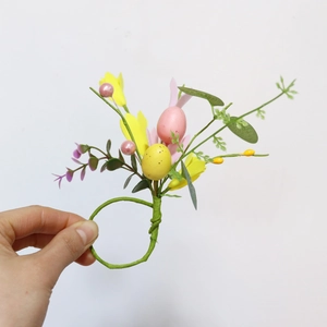 Detail of Easter napkin ring featuring artificial yellow forsythia flowers and speckled eggs