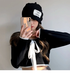 Detail of a black knit beanie with 8 MICRAER patch and matching bow-tie outfit