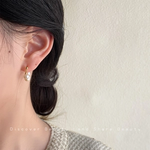 Close-up of elegant baroque pearl earrings in gold setting worn by a model