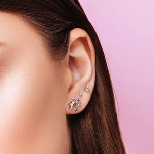 Detailed view of gold vermeil sterling silver dragonfly and floral stud earrings on ear