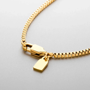 Close-up of gold stainless steel box chain necklace with lobster clasp and tag