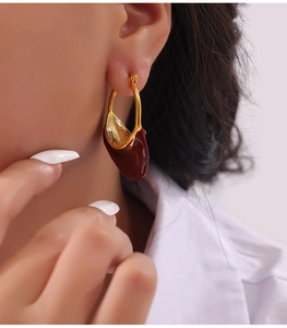 Detail shot of vintage gold teardrop earrings with wine red enamel on a female model