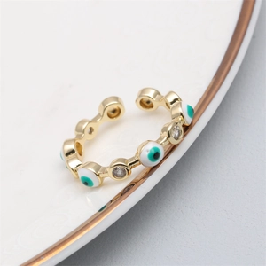 Close-up of gold evil eye open ring with zircon and blue enamel on a ceramic tray