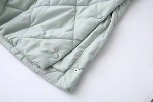 Detail of light green quilted coat showing diamond pattern and matching snap buttons