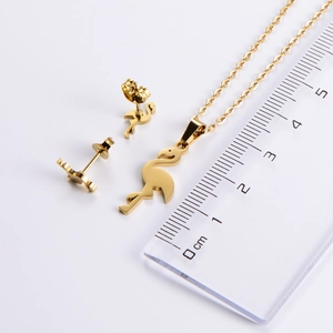 Polished gold flamingo jewelry set with necklace and earrings next to a scale ruler