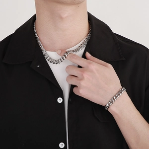 Close-up of polished silver Cuban link necklace and bracelet worn over a black shirt