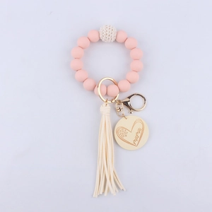 Detail of pink silicone bead bracelet with beige tassel and Mama wood pendant