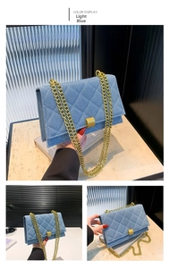 Detail view of light blue denim crossbody bag featuring quilted lattice and gold chain