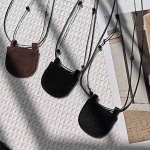 Minimalist leather crescent mini neck bags in black and brown with adjustable cords