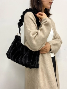 Fashionable black faux fur shoulder bag with wave texture and pompom strap detail