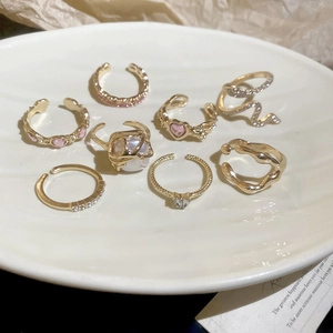 Close-up of a 7-piece gold ring set with pink hearts and sparkling crystals in a ceramic tray