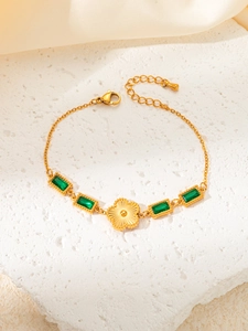 Detail of gold bracelet featuring emerald green zircons and a sunflower pendant charm